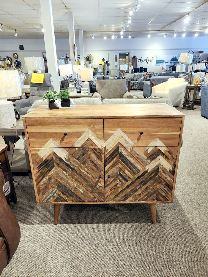 A Crestview Collection Sierra Nevada Cabinet with a geometric mountain pattern stands in a showroom.