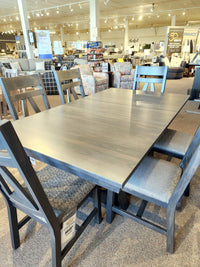 A Handstone BE4260 Belmont Dining Package with six side chairs is on display in a furniture showroom.