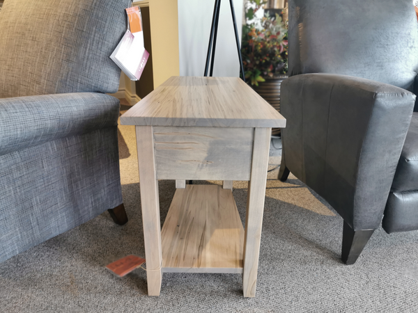 A Handstone N-GG1611 Glengarry Wedge Table with shelf sits between two upholstered chairs in the showroom.