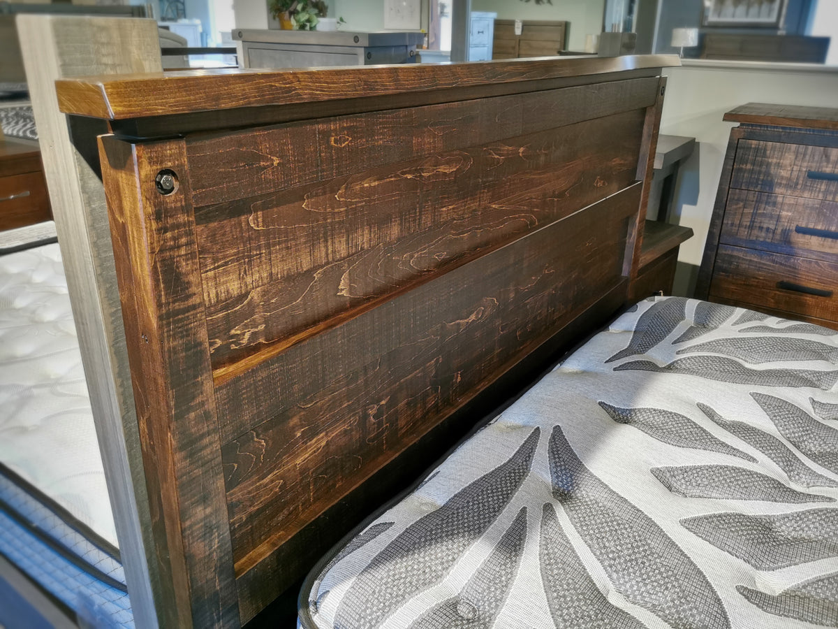 Close-up of the Handstone PE-QL Pemberton Q Bed with sculpted curves and floral bedding displayed in a showroom.