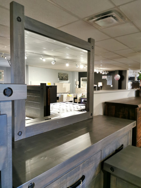 Handstone Rafters Six Drawer Dresser Mirror with metal frame reflects industrial furniture in showroom.