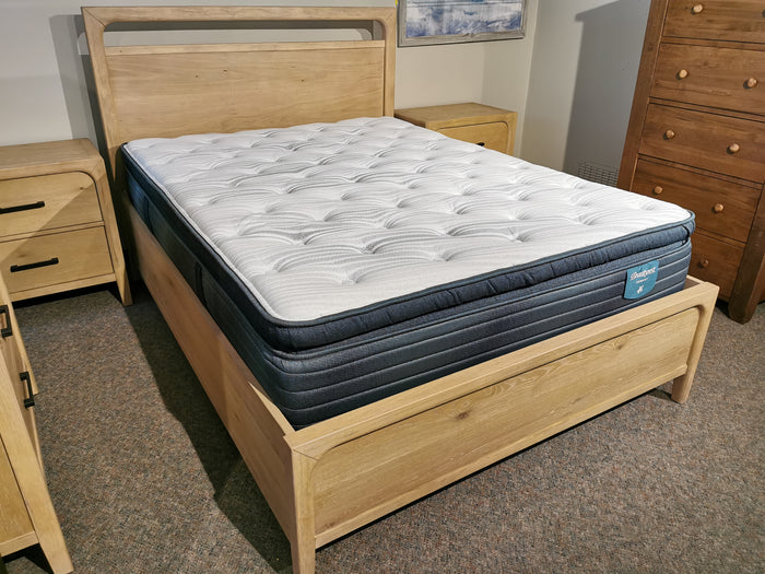 The Magnussen B5684 Somerset Queen Bed Frame features a butternut finish, paired with matching wooden furniture.
