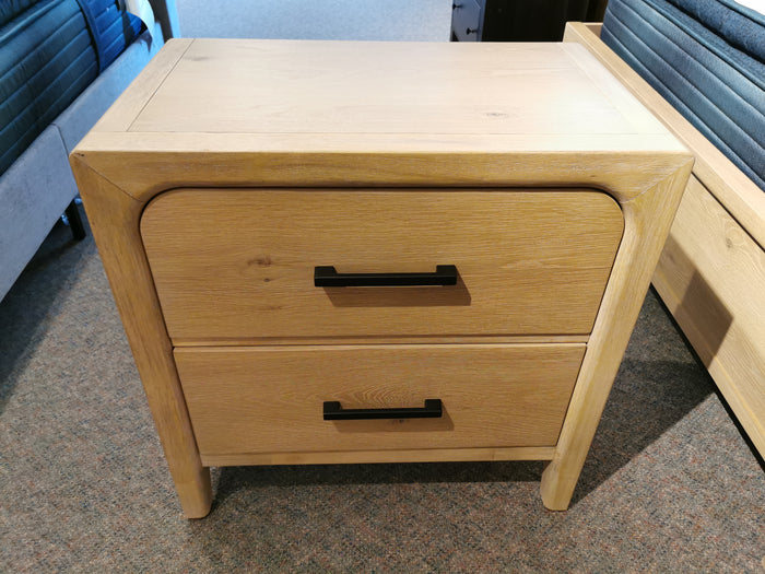 Magnussen B5684 Somerset Nightstand with two drawers, black handles, on carpet by the bed.