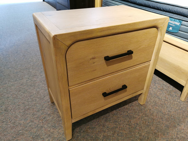 A Magnussen B5684 Somerset Nightstand with black handles and two drawers stands on a carpeted showroom floor.