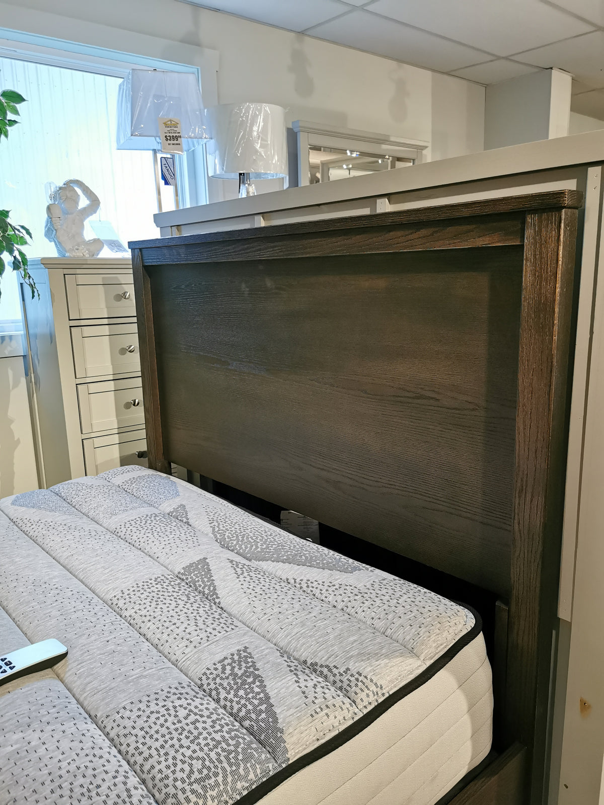 Bedroom showroom with Vaughan Bassett's 11 Fundamental Panel Double Bed, mattress, dresser, lamps, and window.