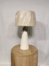 The Lana 2 Pack Table Lamp by Adesso Lamp, with an off-white ribbed base and oatmeal linen shade, sits on a round table.