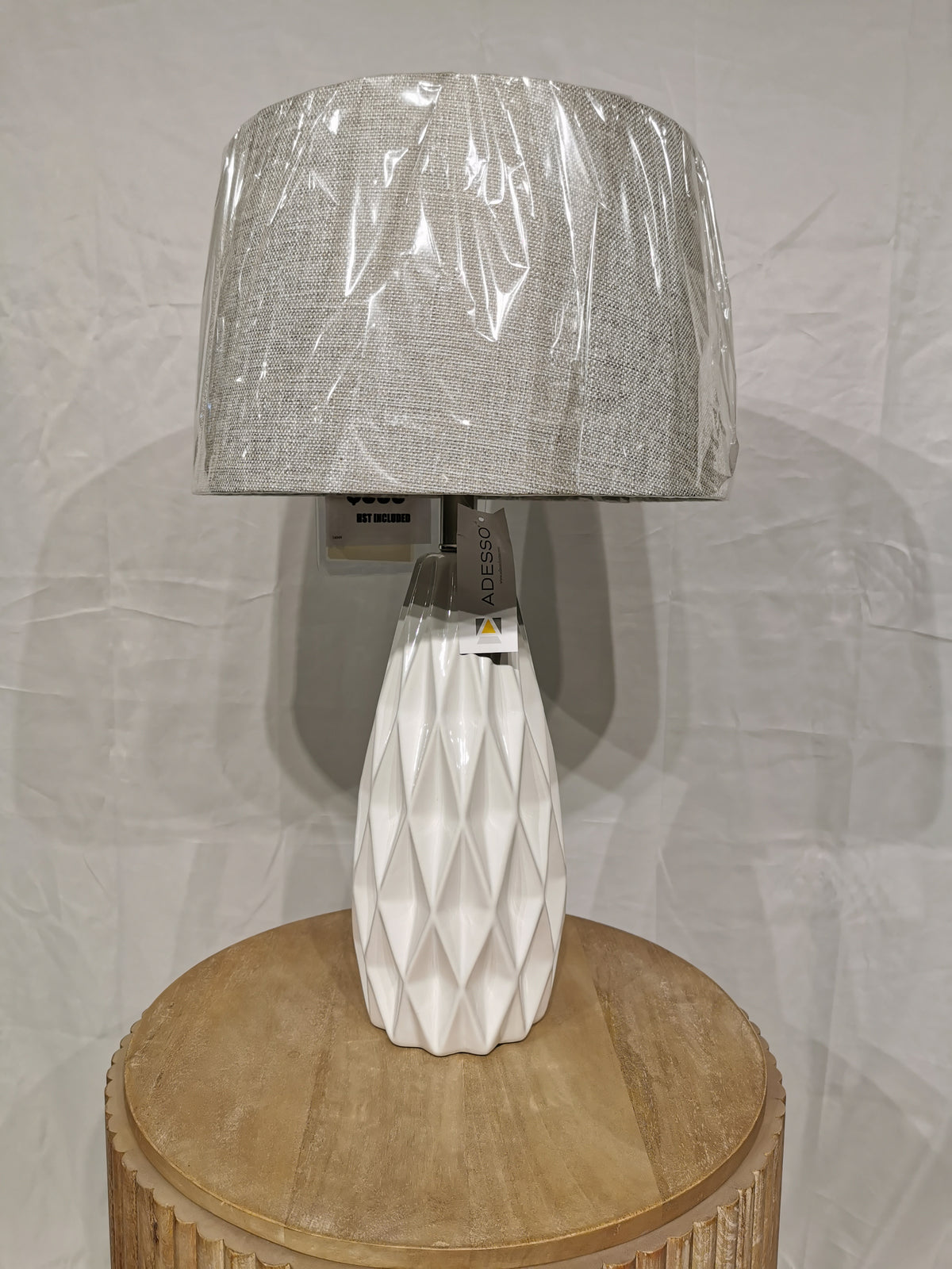 The Adesso Lamp Joan 2 Pack Table Lamp with ceramic base and gray shade is on a round wooden table.