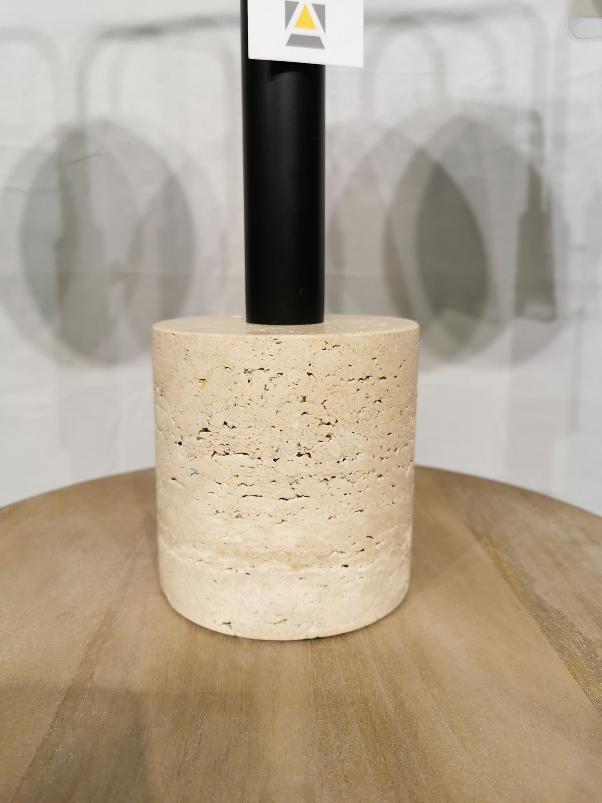 The Adesso Stockton Table Lamp features a beige stone base, black rod, and white glass shade on a wood surface.