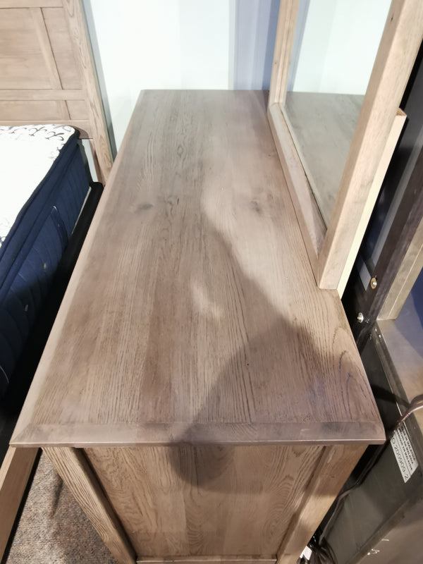 Vaughan Bassett's 123 Custom Express 7-Drawer Dresser in driftwood grey shown with a mirror beside a mattress.