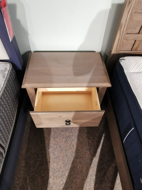 Vaughan Bassett 123 Custom Express nightstand, driftwood grey, solid oak, with one open drawer between two beds.