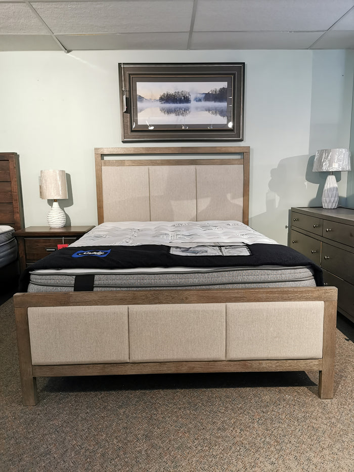 A queen-sized Donald Choi Winston Bed Frame with padded headboard, nightstands, and lamps in a showroom.