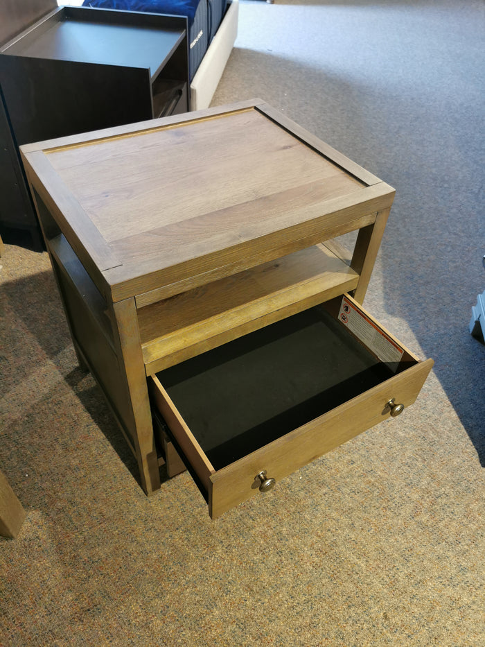 The Donald Choi Winston 2 Drawer Nightstand sits on a carpeted floor, featuring spacious drawers and an open shelf.