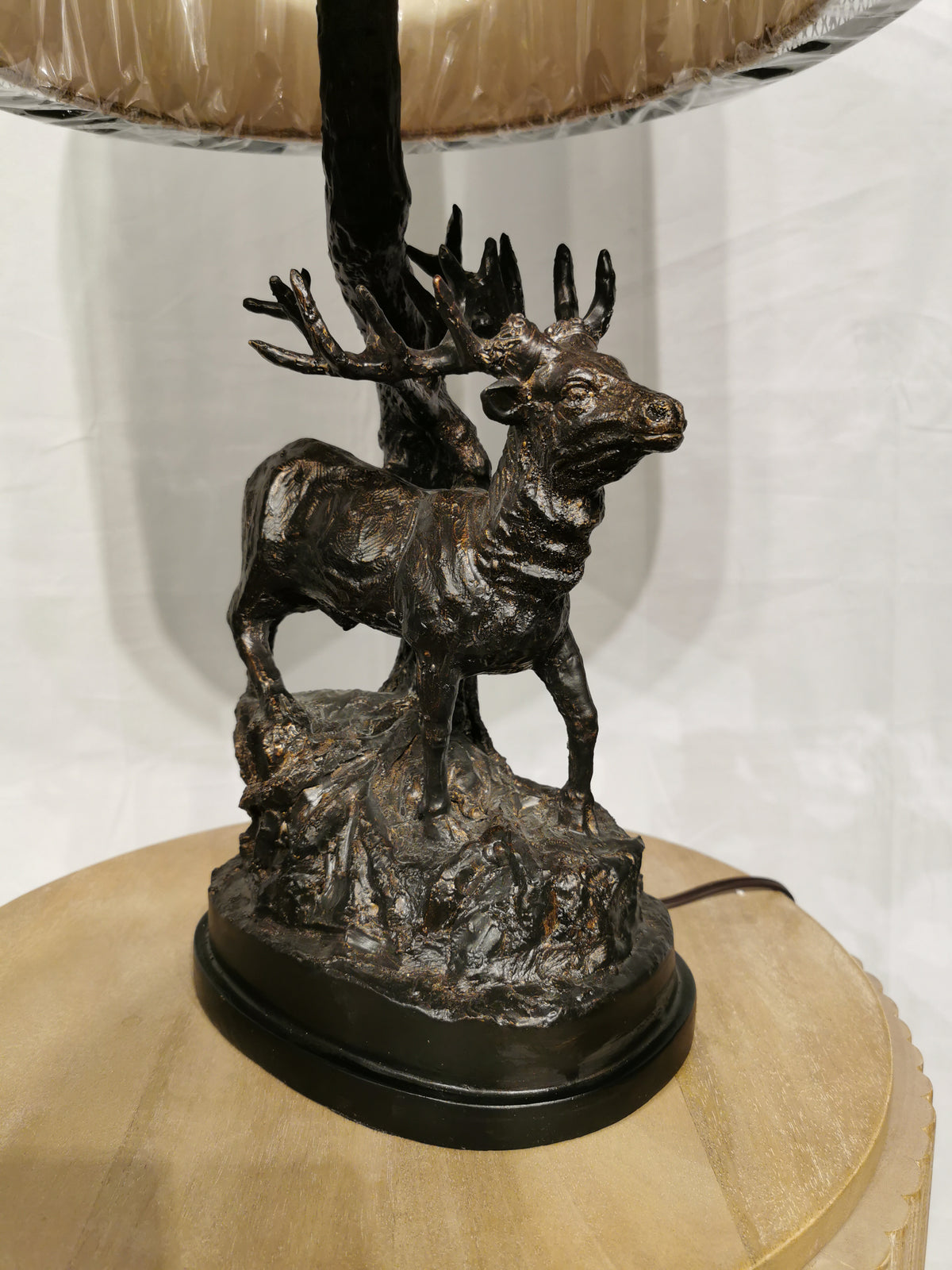 The Crestview Collection Hunters Walk Table Lamp has a bronze deer sculpture base on a rustic wooden table.