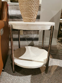 Magnussen T5927 Jennings Round End Table with Weathered Antique Nickel legs and shelf, beside a brown sofa.