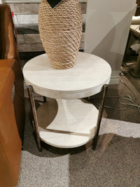 The Magnussen T5927 Jennings Round End Table in Edgecomb Grey with dark legs sits by a sofa on carpet.