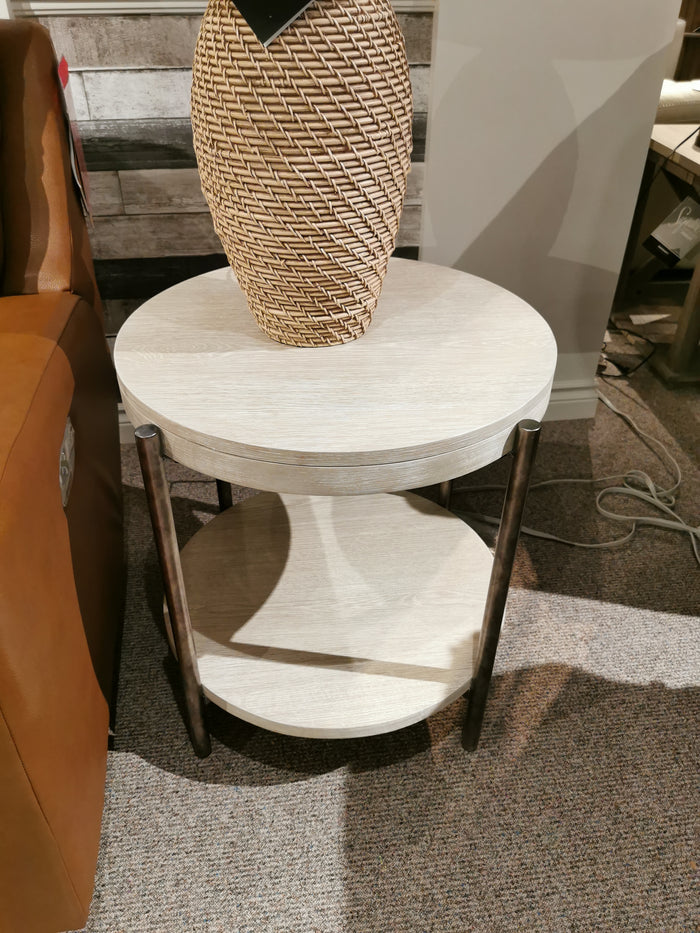 The Magnussen T5927 Jennings Round End Table in Edgecomb Grey with dark legs sits by a sofa on carpet.
