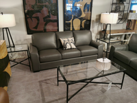 The Kent Sofa by Leather Craft and glass table create style, enhanced by floor lamps and abstract DIMENSIONS on the wall.