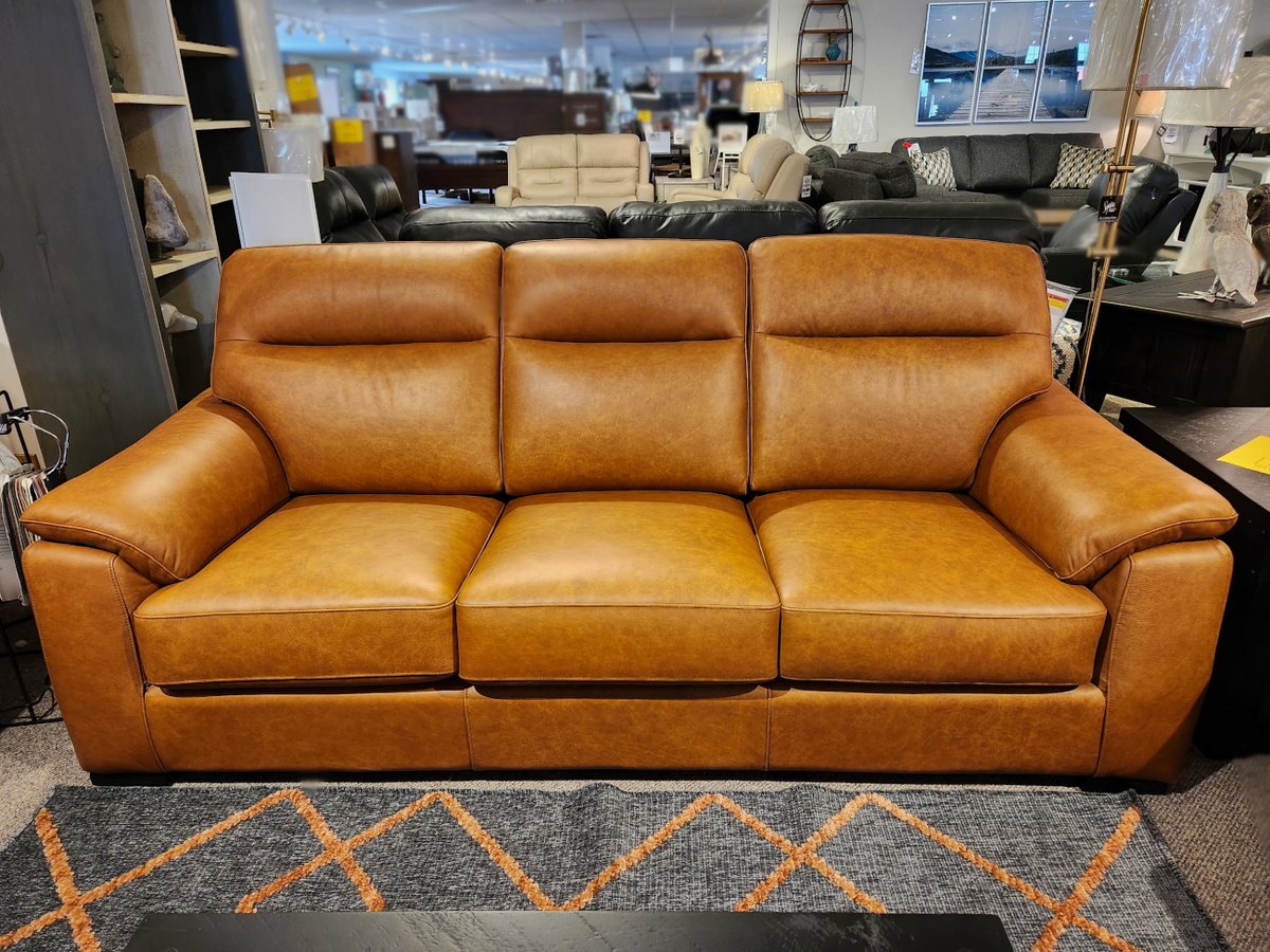 Leather Craft's Norway Leather Sofa, a brown top-grain three-seater, displayed on a patterned rug in the store.