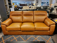 Leather Craft's Norway Leather Sofa, a brown top-grain three-seater, displayed on a patterned rug in the store.