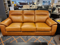 The Leather Craft Norway Leather Sofa is displayed in a showroom on a rug with an orange diamond pattern.