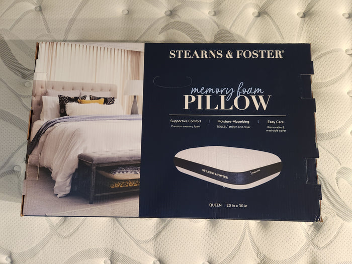 A box of the Stearns & Foster Memory Foam Pillow rests on the mattress, featuring an inviting bedroom image. This pillow's conforming memory foam design offers comfortable support to ensure restful nights.