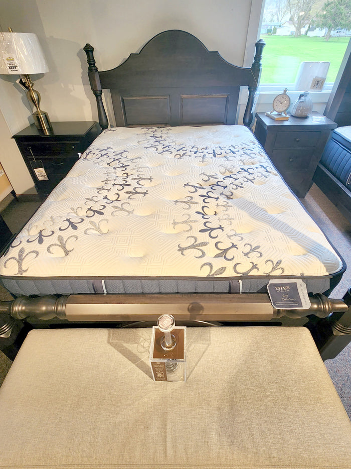 A showroom bed with a Stearns & Foster Mon Tresor Firm mattress, bedside tables, lamp, and decorative bottle on the bench.
