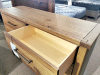 The Vaughan Bassett 752 Dovetail 8-Drawer Dresser in White Oak sits on a carpeted floor in a store.