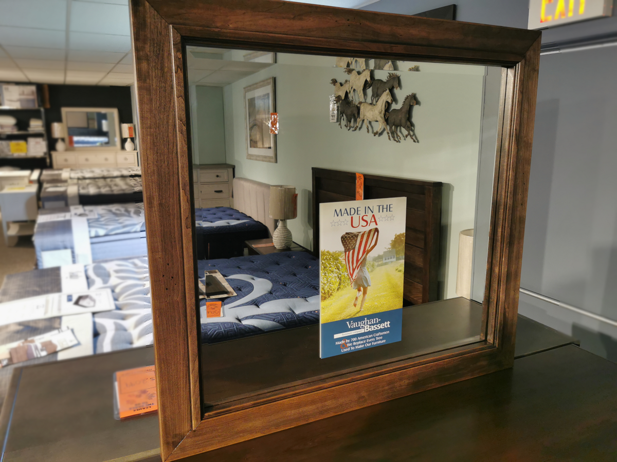 The Vaughan Bassett Landscape Lancaster Mirror reflects beds and a wall decoration with running horses.