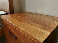 The Vokes Rocklynd 2 Drawer Night Stand features a smooth surface and dark handle for a modern bedside look.
