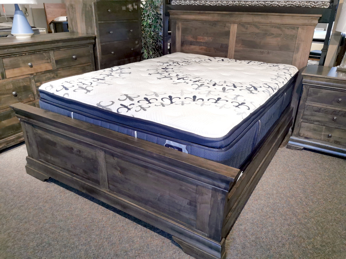 A Vokes 262 Bayshore Queen Panel Bed with paneled headboard, dressers, and nightstand displayed in showroom.