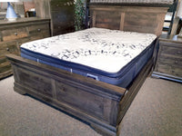 A Vokes 262 Bayshore Queen Panel Bed with paneled headboard, dressers, and nightstand displayed in showroom.