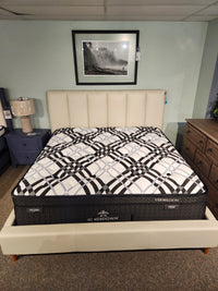 A KingsDown Vermillion ET Firm Mattress, queen size, on a cream bed frame for optimal sleep, in showroom display.