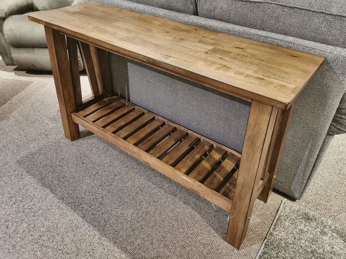 The Winners Only NP100S Newport Sofa Table adds charm to the gray sofa on the carpeted floor.