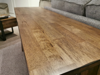 The Newport Sofa Table by Winners Only is placed near a gray sofa on a carpeted floor.