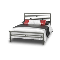 The Orson Bed Frame by Amisco is a contemporary bed featuring a sleek metal frame with a geometric headboard, beautifully complemented by striking black, red, and white bedding and pillows.