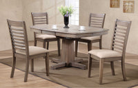 The Ventura Pedestal Table by Winners Only with four chairs, vase, and cups sits on a Santa Fe brown rug.