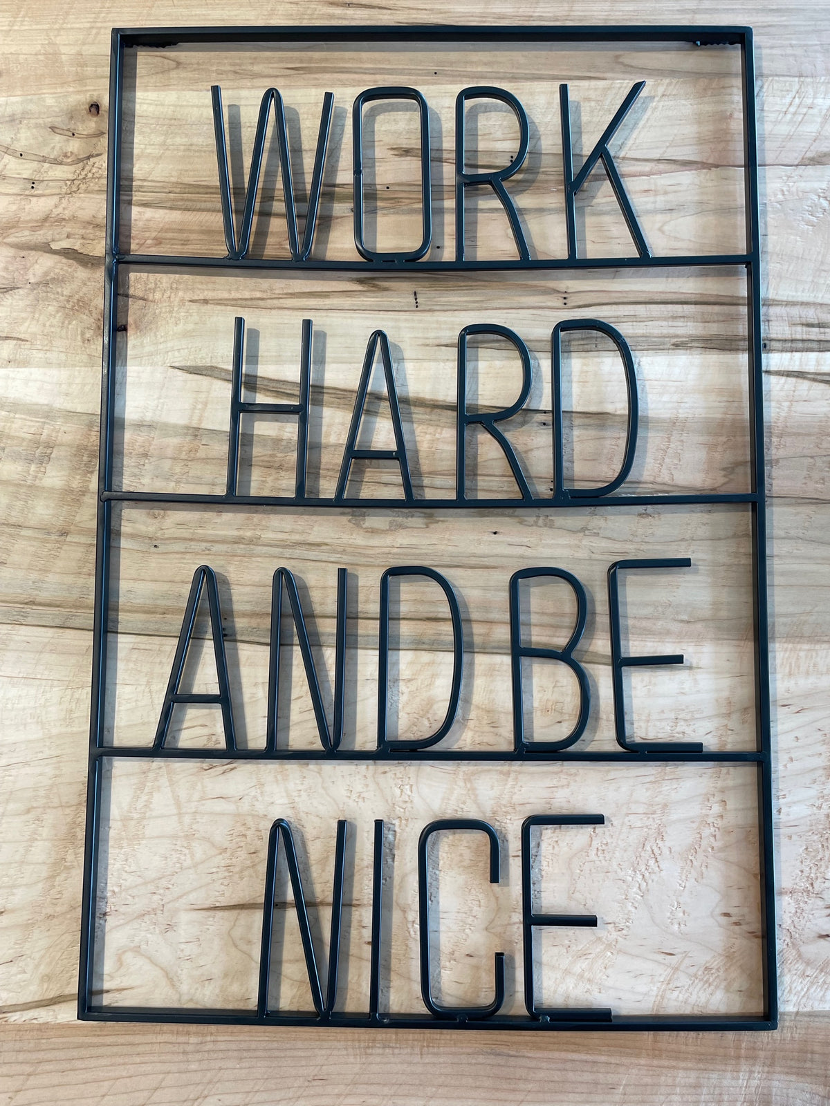 Mercana's "Work Hard and Be Nice" sign features a wooden background with a matte black finish.