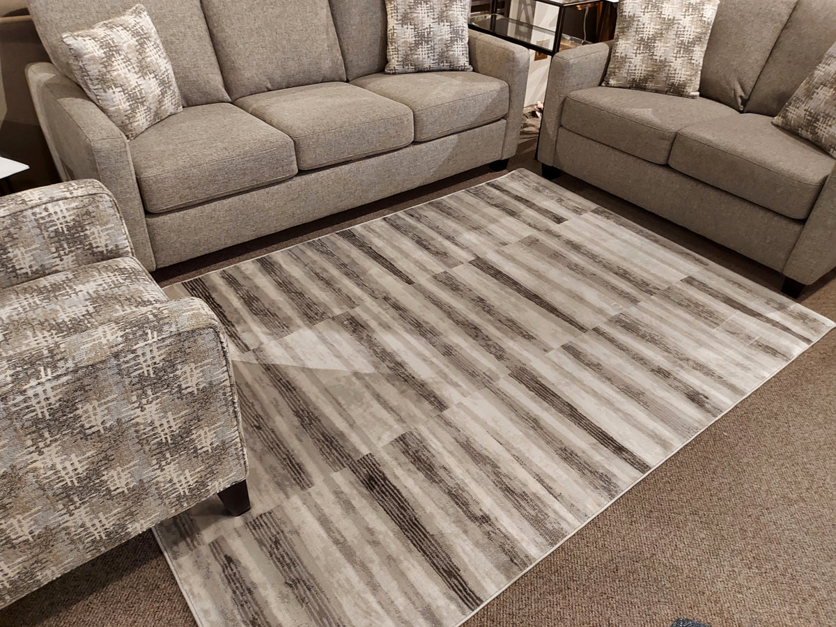 Kalora Chorus 3694/13 Mid-Century Modern grey and white geometric rug accents a gray sofa set with patterned pillows.
