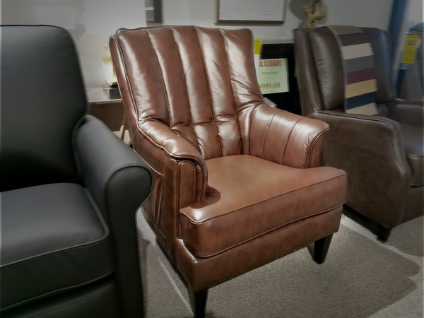 The 786 High Leg Chair by Leather Craft, a classic brown tufted armchair, flanked by two others, is showcased in the showroom.