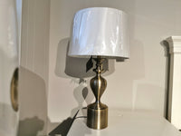 The Pacific Coast 87-7773-02 Brazza Table Lamp with a linen shade sits on a white surface by a beige wall.