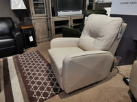 The Palliser 42002 Theo Wall-hugger Recliner offers luxurious comfort on a showroom's patterned rug, amidst chairs and cabinets.