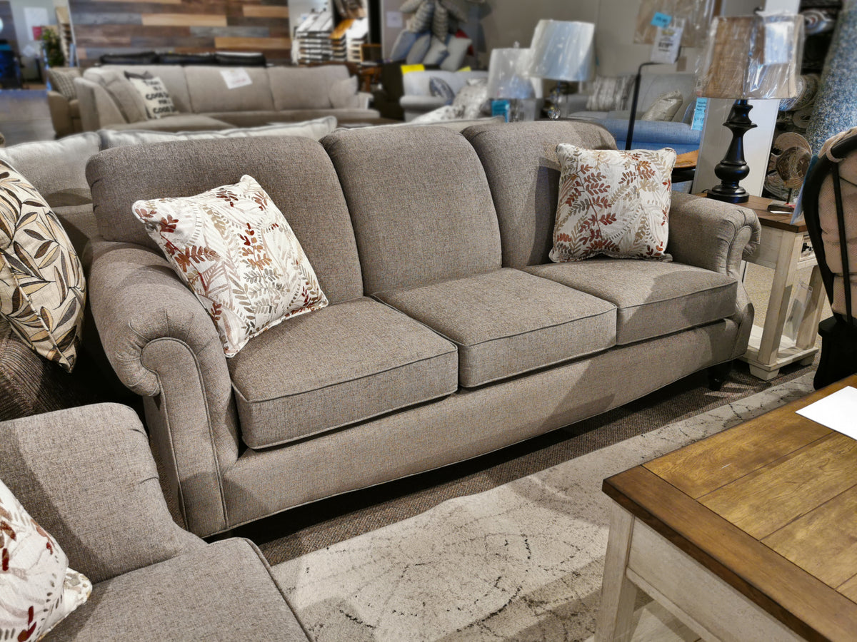 Superstyle's 7303 Sofa, a Canadian gray upholstered piece with polyester fabric, comes with two patterned throw pillows.