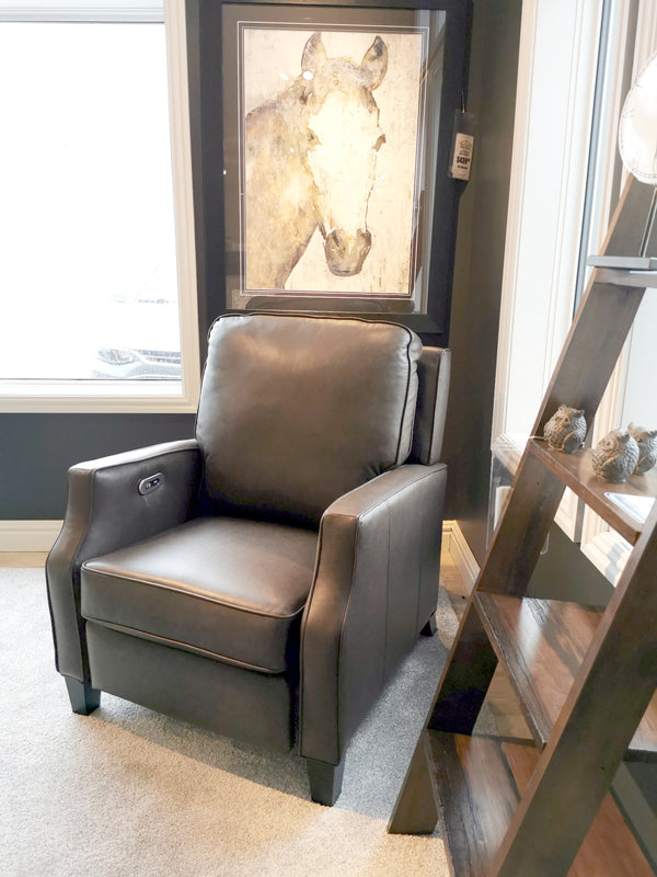 The L86 Leather Power Recliner by Superstyle in gray sits by a window, before a horse painting and wooden shelf.