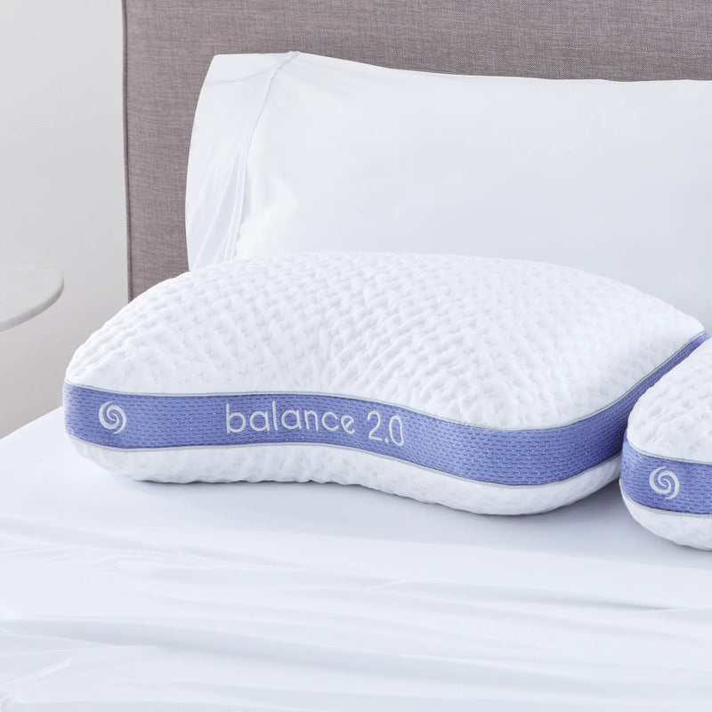 A Bed Gear Balance Cuddle Pillow with Air-X mesh and a purple band sits on a bed with crisp white linens.