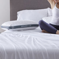 Person stretching on a bed with a Bed Gear Storm Cooling Pillow, white headboard, and breathable white bedding.