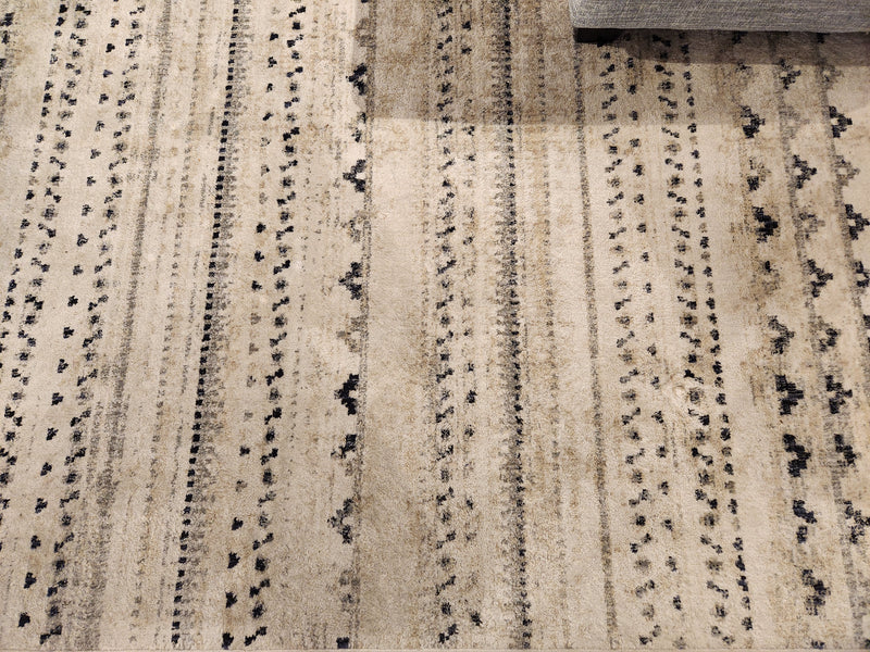 Kalora Serene D201/7454 5'3" x 7'7" beige area rug with black and white modern pattern; gray sofa in upper right.