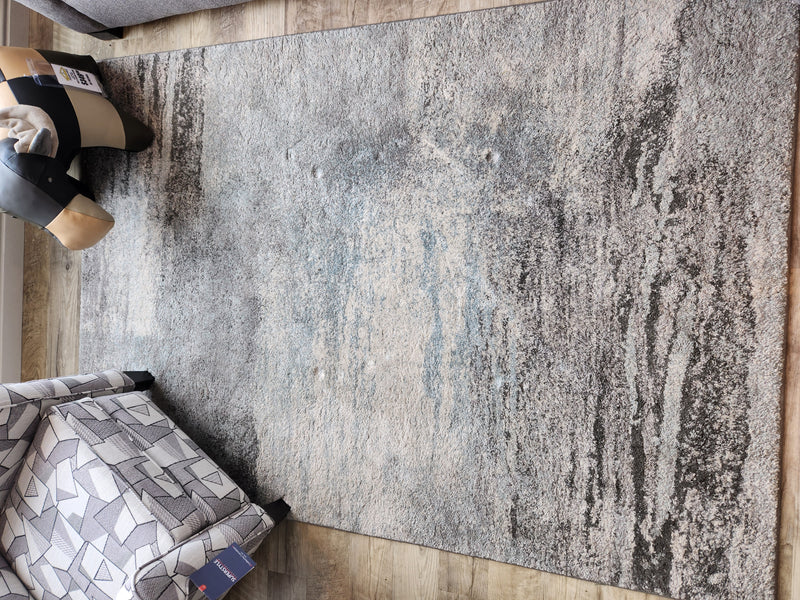 The Kalora Breeze 2495/1324 5'3" x 7'7" area rug features a modern grey blue streak pattern, perfect for home decor.