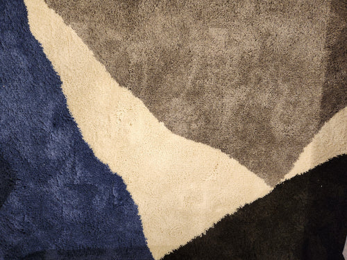 A close-up of the Maroq 9709/T434 carpet by Kalora featuring a modern abstract design with blue, beige, and gray geometric shapes.