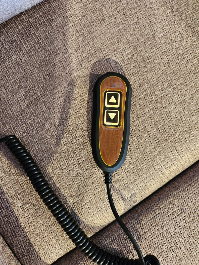 A remote for the Golden Antler Elara Zone 1 Lift Chair sits on textured brown fabric.