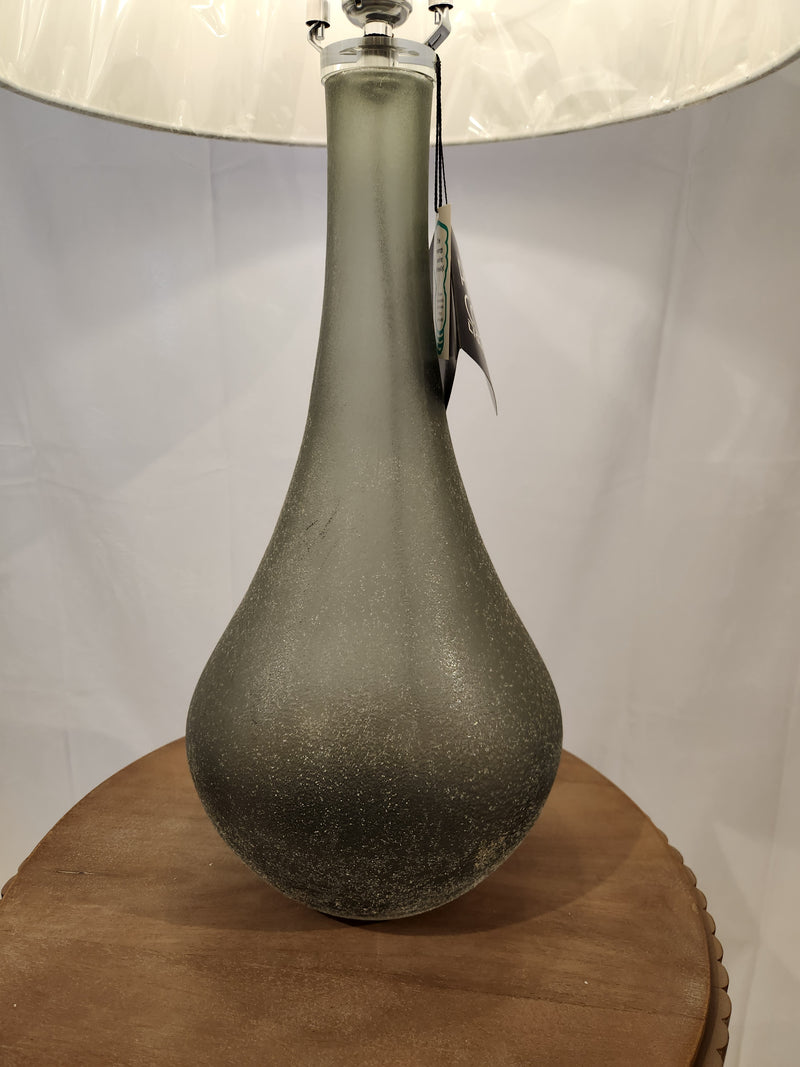 The Pacific Coast 87-7776-78 City Shadow Table Lamp has a teardrop frosted blue grey glass base on a round wood table.